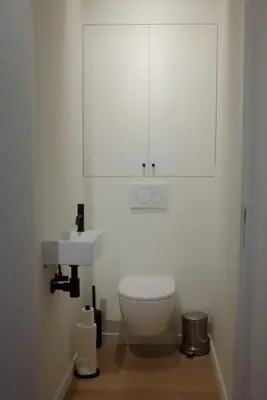 a white bathroom with a toilet and a sink at Design appartement met zonnig terras bij Gravensteen in Ghent