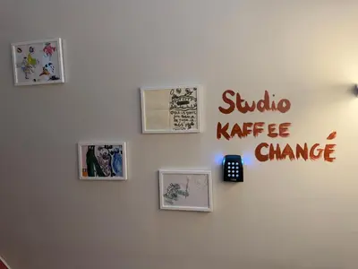 a wall with pictures and a clock on it at Kaffee Changé in Ghent