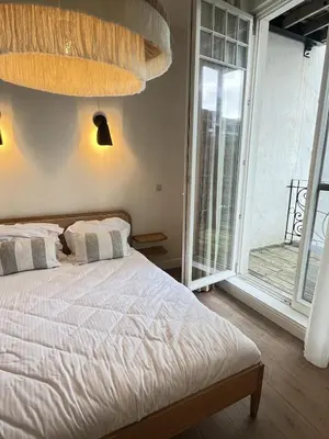 a bedroom with a bed and a large window at Maison Violette Antwerp in Antwerp