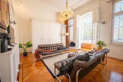 a living room with leather couches and a chandelier at Master Suite Le Monarque Antwerp in Antwerp