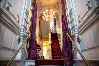a staircase with purple curtains and a chandelier at Le Nymphale Suite Antwerp in Antwerp