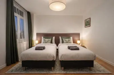 two twin beds in a bedroom with two lamps at Luma Residence in Brussels