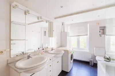 a white bathroom with two sinks and a washing machine at Prime Location Apartment Chtelain Saint-Gilles Self checkin in Brussels