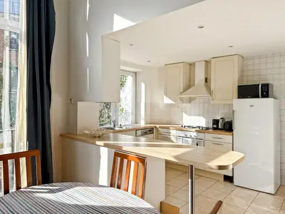 a kitchen with white cabinets and a table with chairs at Prime Location Apartment Chtelain Saint-Gilles Self checkin in Brussels