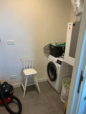 a laundry room with a washing machine and a chair at Apartment in Lochristi, close to Ghent & Lokeren! in Lochristi