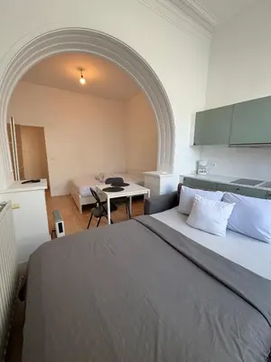 a bedroom with a bed and a table and a kitchen at Le sily appartement Bruxelles centre-ville in Brussels