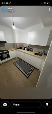 a kitchen with white cabinets and a wooden floor at Un cocon chaleureux in Brussels
