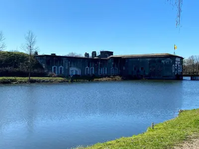 an old building sitting next to a body of water at Erflogies Fort Liezele