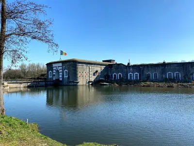 an old building sitting next to a body of water at Erflogies Fort Liezele