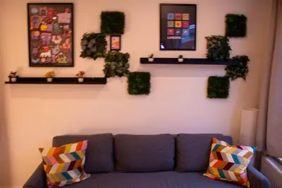 a living room with a couch and some plants on a wall at Zoe's world in Brussels