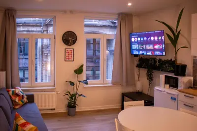 a living room with a blue couch and a tv at Zoe's world in Brussels