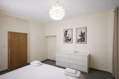a bedroom with a bed and a dresser and a chandelier at Central Brussels Spacious 2BR near Grand Place3 in Brussels