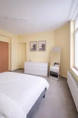 a bedroom with a white bed and a chair at Central Brussels Spacious 2BR near Grand Place3 in Brussels