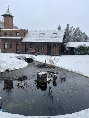 a pond in front of a building in the snow at Aplusstudio in Zottegem
