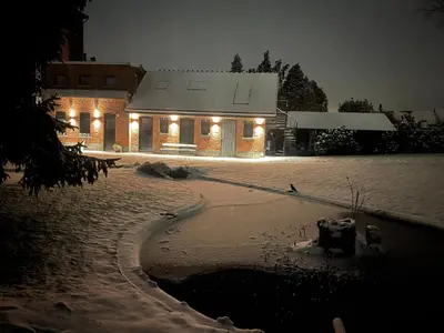 a house with lights on in the snow at night at Aplusstudio in Zottegem