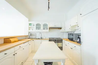 a kitchen with white cabinets and a white table at Bed & Port luxury villa in Kallo