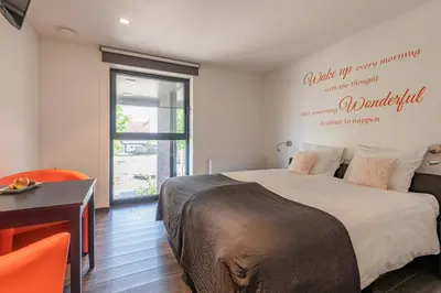 a bedroom with a bed and a desk and a window at B&B Molmento in Mol