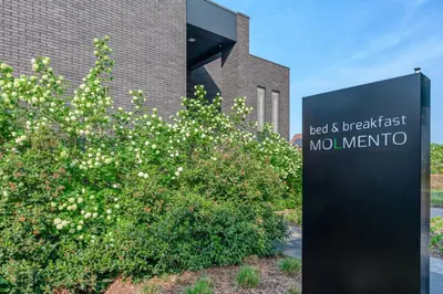 a sign in front of a building with a bush at B&B Molmento in Mol