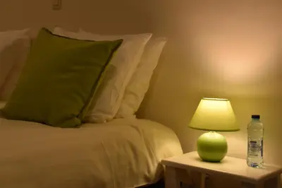 a bed with a green lamp and a bottle of water at RectoVersoVV in Sint-Pieters-Leeuw