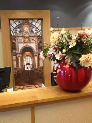 a red vase with flowers sitting on a counter with a mirror at Trip Inn Eden Antwerpen in Antwerp