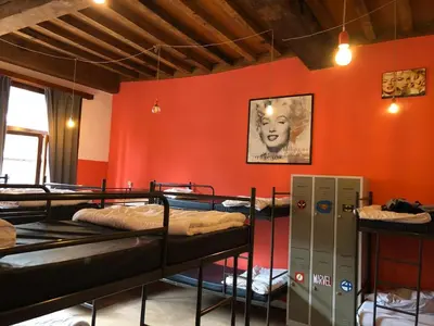 a room with three bunk beds in a room with orange walls at Antwerp City Hostel in Antwerp