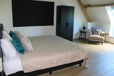 a bedroom with a large bed and a chair at De Blauwe Hoeve in Zwijndrecht
