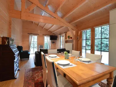 a dining room and living room with a wooden table at Peaceful Chalet Retreat in Nijlen