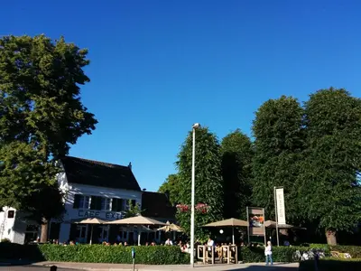 a building with tables and umbrellas in front of it at Bed & Breakfast Exterlaer in Antwerp