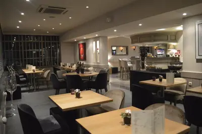 a restaurant with tables and chairs and a bar at Hotel The New Fox in Affligem