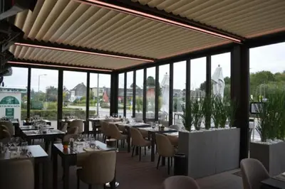 a restaurant with tables and chairs and windows at Hotel The New Fox in Affligem