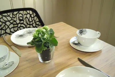 a wooden table with plates and a cup and a plant at Bed & Breakfast De Kleine Magnolia in Tessenderlo