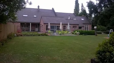 a house with a yard with green grass at Bed & Breakfast De Kleine Magnolia in Tessenderlo