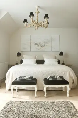 a bedroom with a large white bed with two benches at B&B Interludium in Nijlen