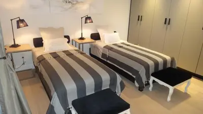a room with two beds and two chairs and lamps at B&B Interludium in Nijlen