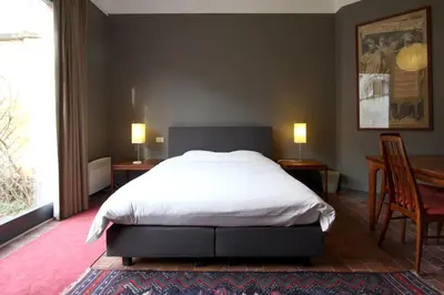 a bedroom with a bed and two chairs and a window at Baeten's bed and breakfast in Ghent