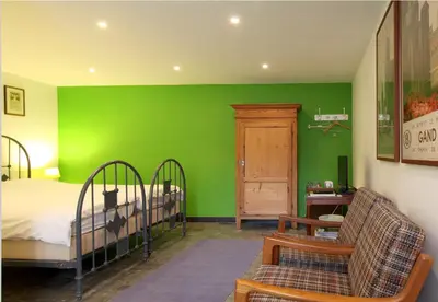 a bedroom with green walls and a bed and a couch at Baeten's bed and breakfast in Ghent