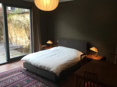 a bedroom with a bed and a table and a window at Baeten's bed and breakfast in Ghent
