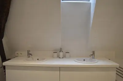 a white bathroom with two sinks and a mirror at De Waterzooi Lodge in Ghent
