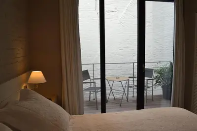 a bedroom with a bed and a balcony with a table and chairs at De Waterzooi Lodge in Ghent