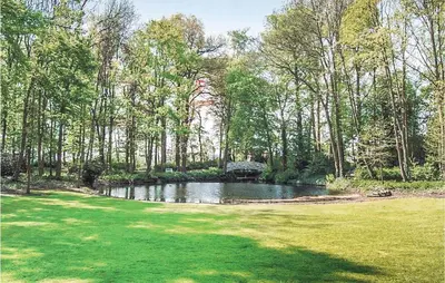 a pond in the middle of a field with trees at Kasteel Ter Leyen in Boekhoute