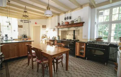 a kitchen with a wooden table and a dining room at Kasteel Ter Leyen in Boekhoute