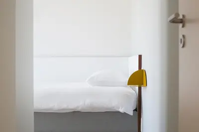 a bedroom with a white bed and a yellow lamp at Cadix 35 in Antwerp