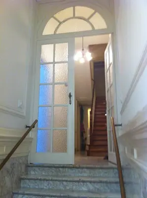a hallway with a door with a window and stairs at Résidence18 in Brussels