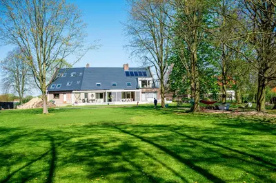 a house with a blue roof with a green yard at Aquarand in Hofstade