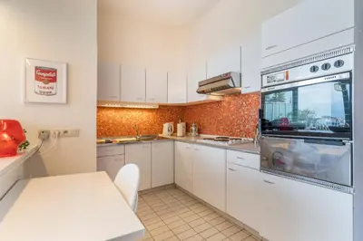 a small kitchen with white cabinets and a white table at Fuths Loft Penthouse 85 in Antwerp