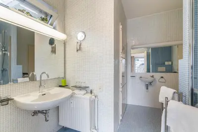 a white bathroom with a sink and a mirror at Fuths Loft Penthouse 85 in Antwerp