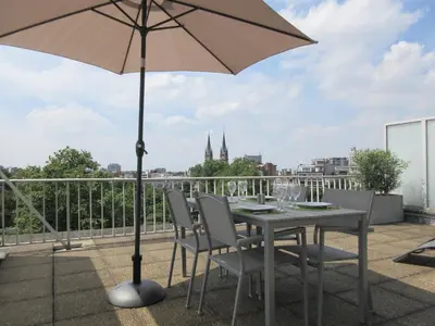 a table and chairs with an umbrella on a balcony at Fuths Loft Penthouse 85 in Antwerp