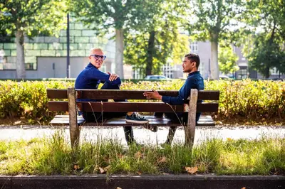 two men sitting on a bench in a park at Fred&Breakfast in Ghent