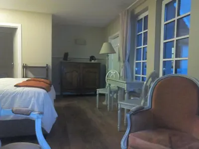 a bedroom with a bed and a chair and windows at Bed and Breakfast Ros & Marc in Wezembeek-Oppem