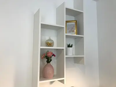 a white book shelf with a vase with flowers in it at Antwerp Business Suites in Antwerp